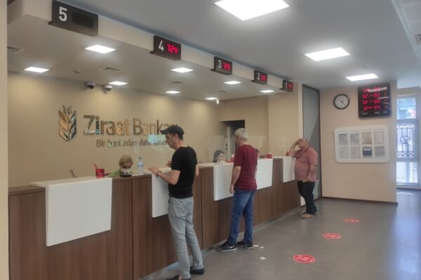 Professionelle Frau mit kurzen Haaren und Brille arbeitet an einem Laptop in einem modernen Büroumfeld