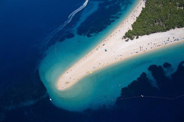 Wunderschöner Sonnenuntergang am Strand von Golden Horn in Kroatien mit klarem, blauem Wasser und felsigen Klippen.