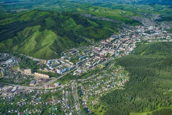 Blick auf die Berge in Gorno-Altaysk mit einem abhebenden Flugzeug der S7 Airlines.