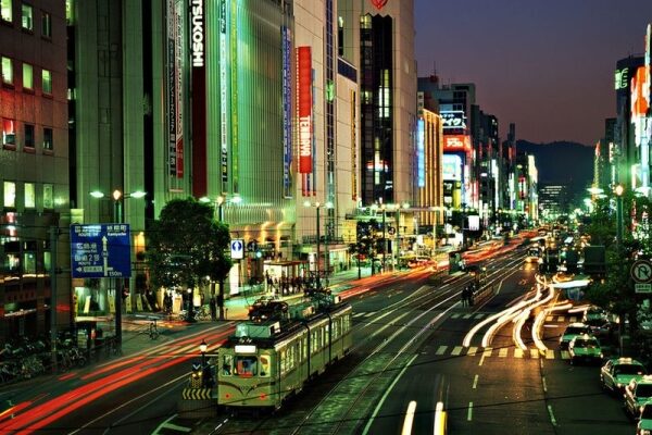 Futuristische Stadtlandschaft in Japan mit moderner Architektur und Neonlichtern, die sich auf dem Wasser spiegeln.