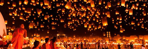 Close up of a fresh berry smoothie served in a clear glass surrounded by blueberries, strawberries, and mint leaves.