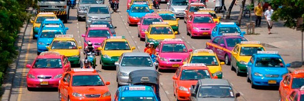 A bright and colorful floral arrangement of various flowers in a glass vase on a wooden table.