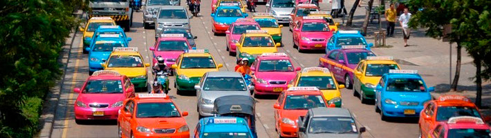 Ein helles und buntes Blumenarrangement mit verschiedenen Blumen in einer Glasvase auf einem Holztisch.